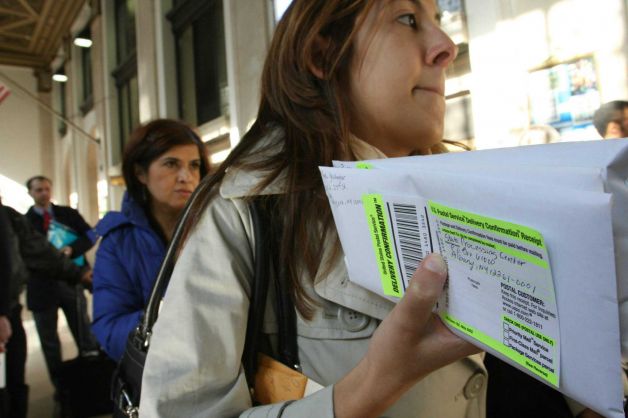 FILE - In this April, 15, 2008, file photo, Dana Pinero, of New York, foreground, waits in line to mail tax returns for both herself and her boyfriend at the James A. Farley Main Post Office in New York. The package of tax increases and spending cuts known as the “fiscal cliff” takes effect on January 1, 2013, unless Congress passes a budget deal by then. The economy would be hit so hard that it would likely sink into recession in the first half of 2013, economists say. Photo: Tina Fineberg / AP